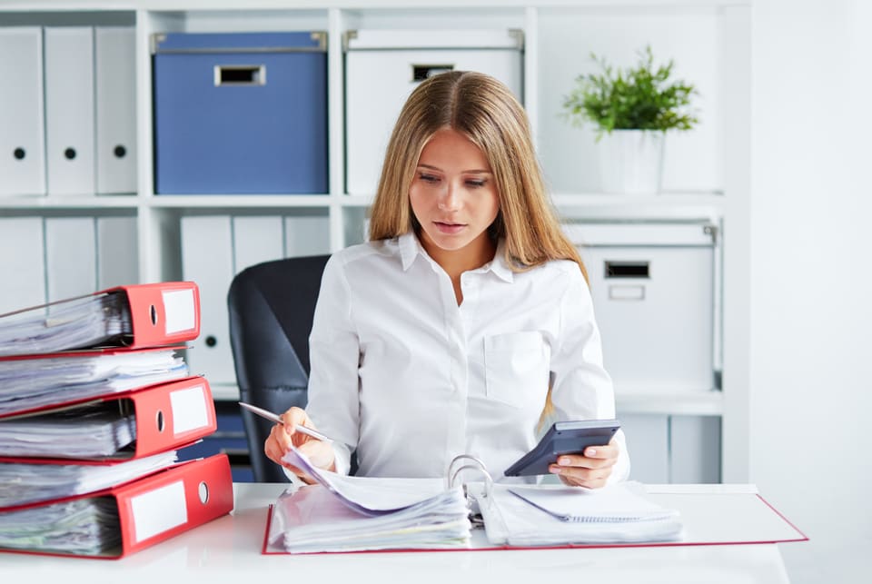 A woman at a desk with folders, reading a document