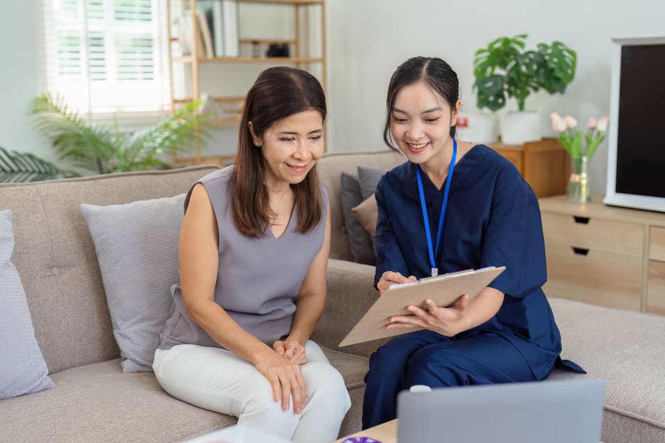 A care worker going through a plan on a tablet with an older woman
