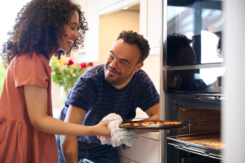 A young woman and a young man baking together in a kitchen