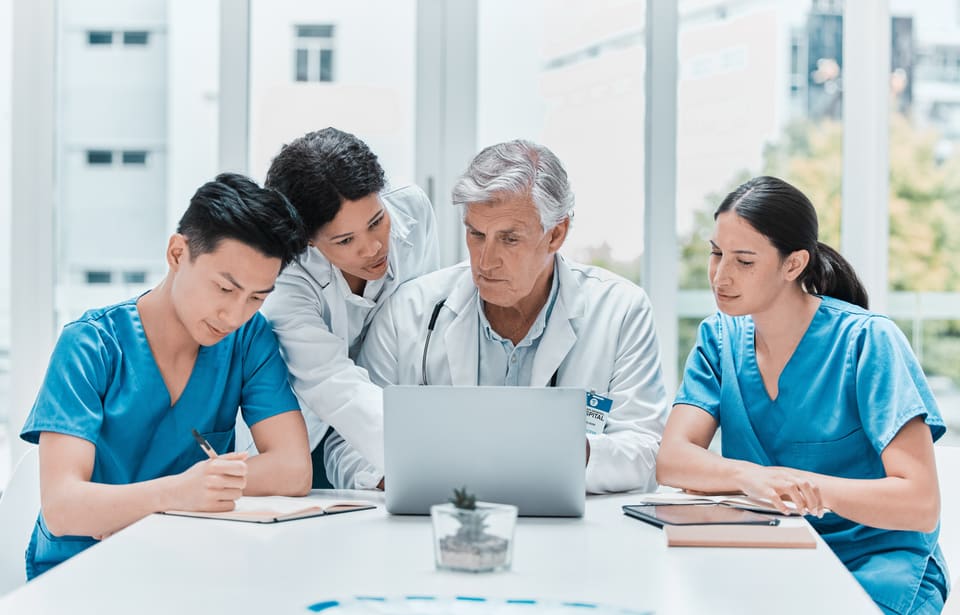 A care team reviewing records together at a laptop