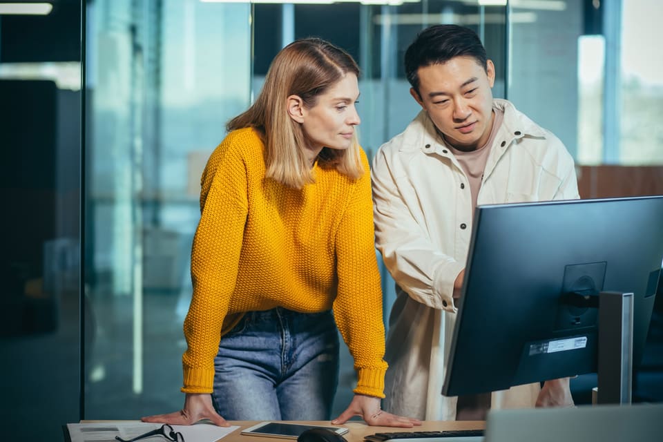 Two colleagues at a desktop screen, working out together who takes a shift