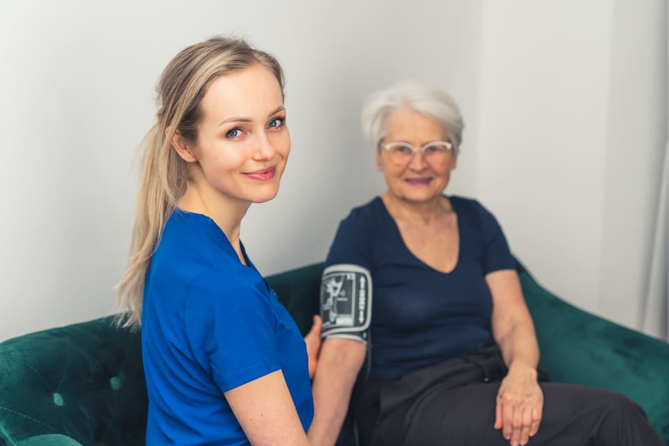 A nurse and an older woman smiling at home