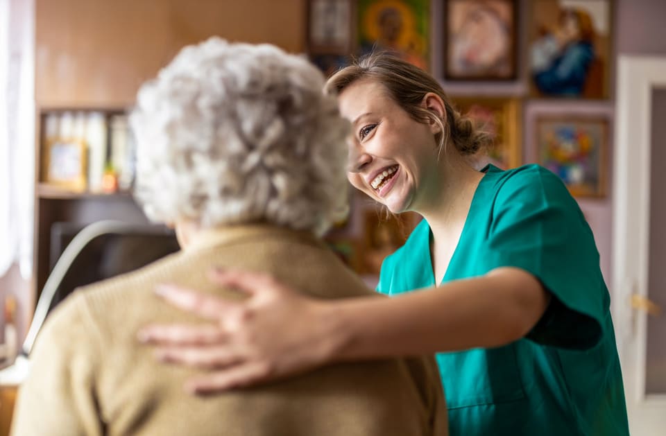 A nurse talking with an older woman at home