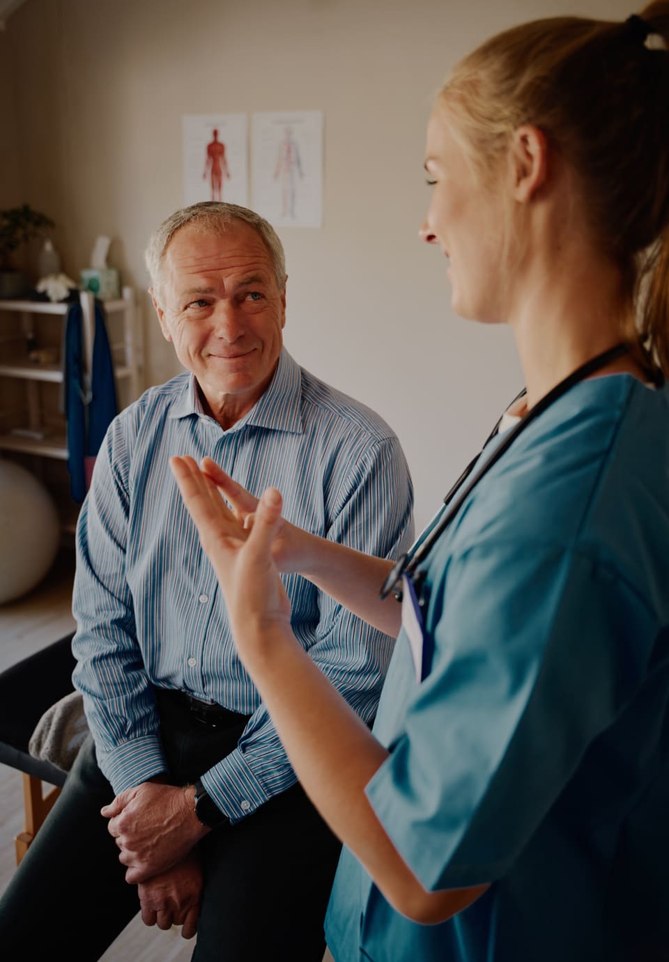 A nurse talking an older man through something in a consulting room