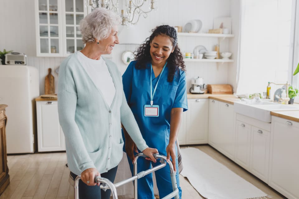 A care worker walking with an older woman using a walker