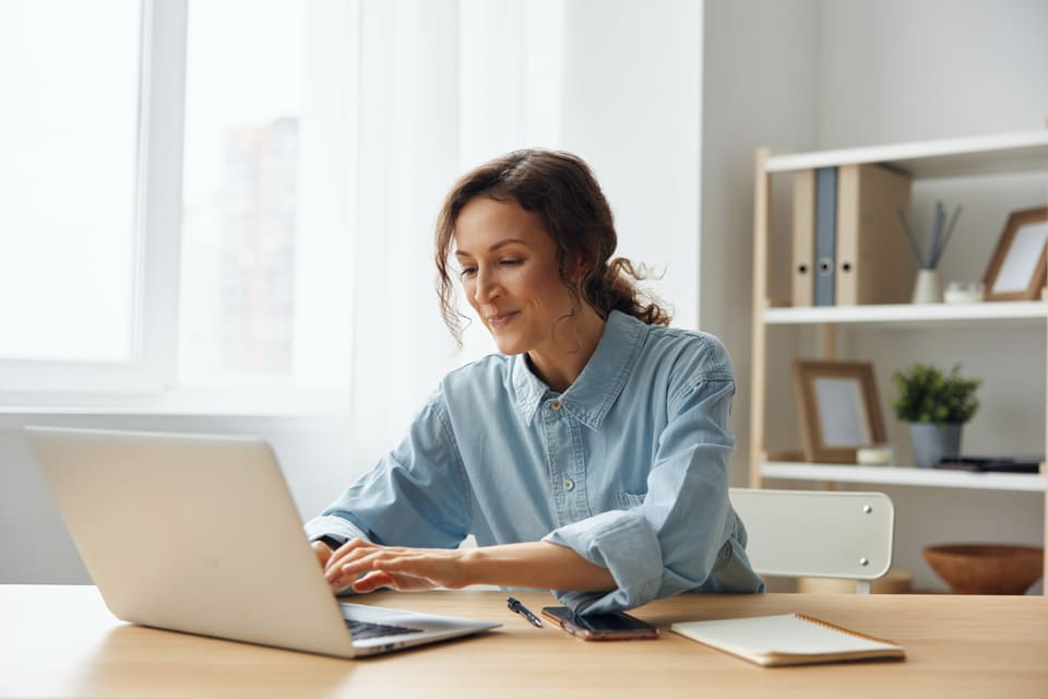 A woman smiling at her laptop