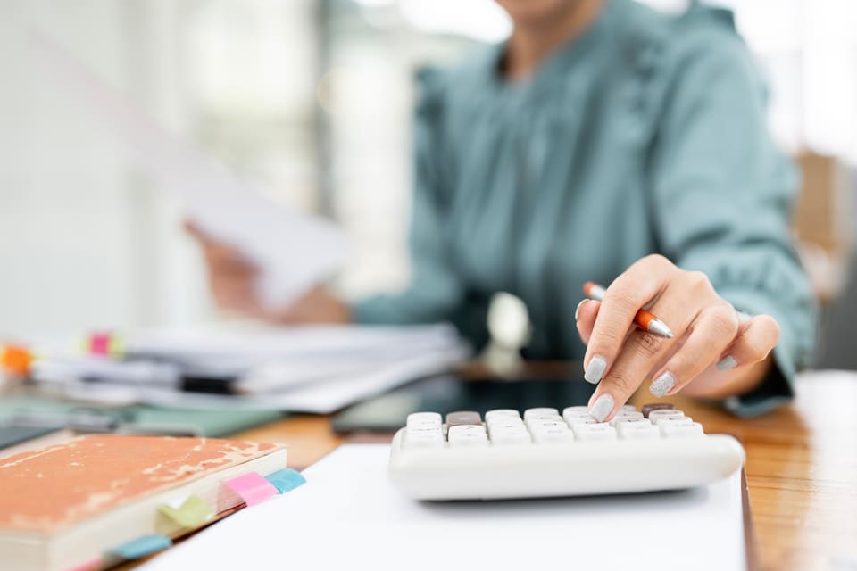 A woman working with a calculator at her desk