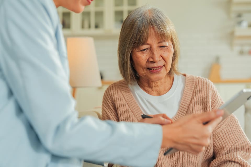 A care worker showing an older woman something on a tablet