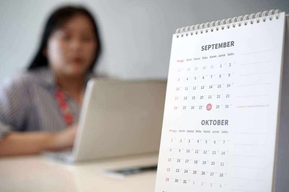 A woman working at her desk beside a desk calendar