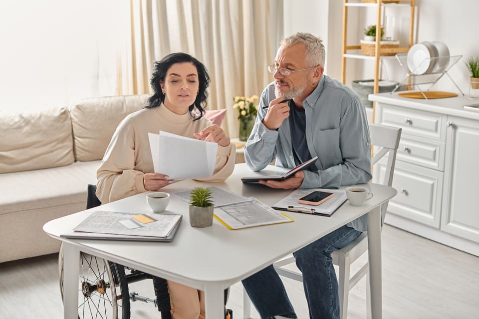 A woman and an older man going through papers at a kitchen table