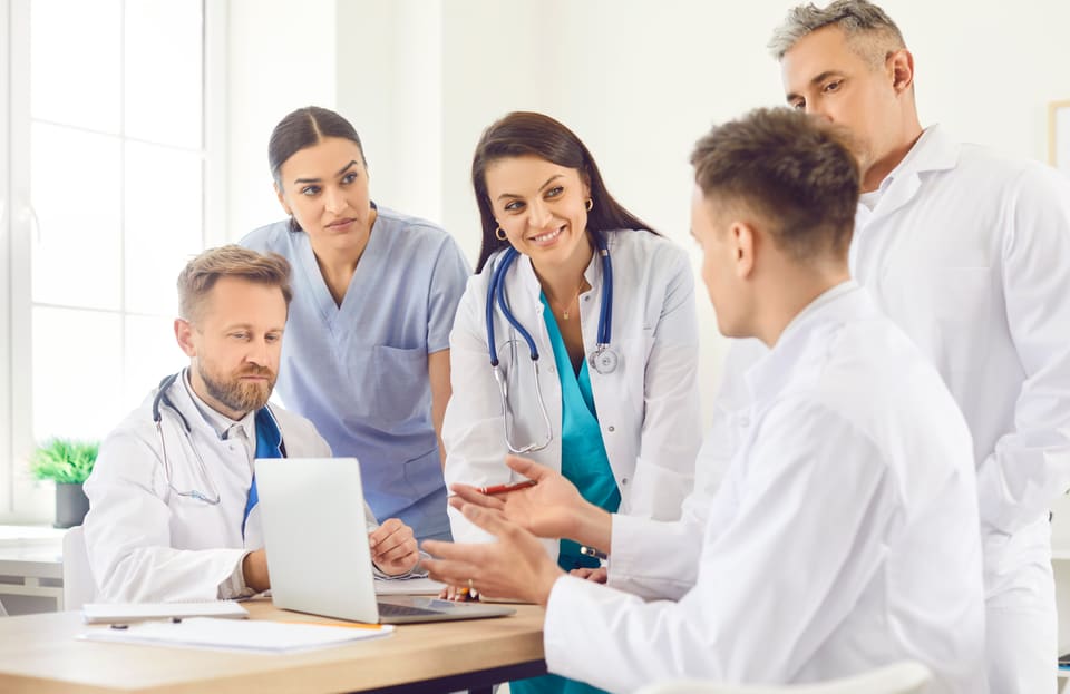 A care team gathered around a laptop