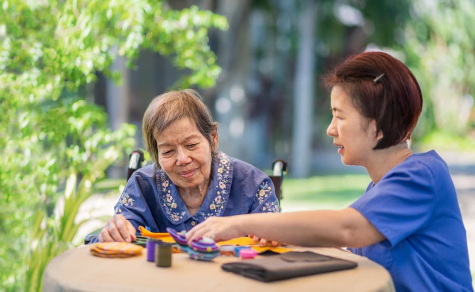 An occupational therapist working with an older woman at a table