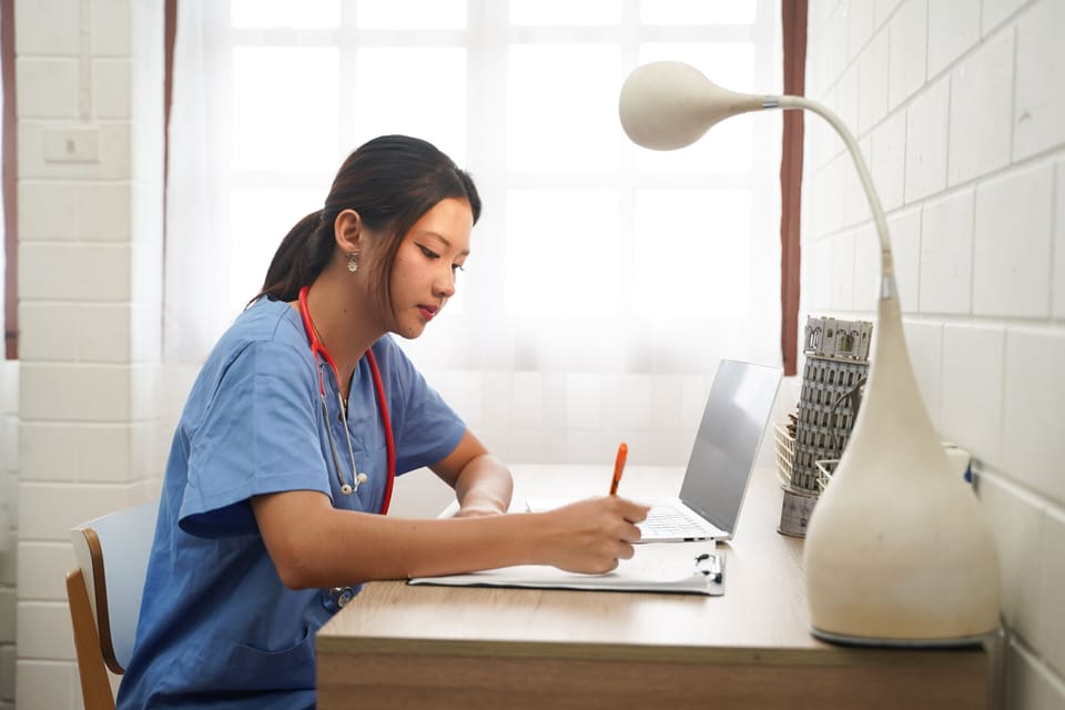A clinician writing notes at her desk
