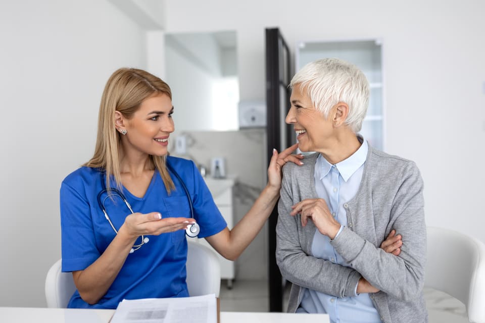 A nurse talking with an older woman in a clinic room