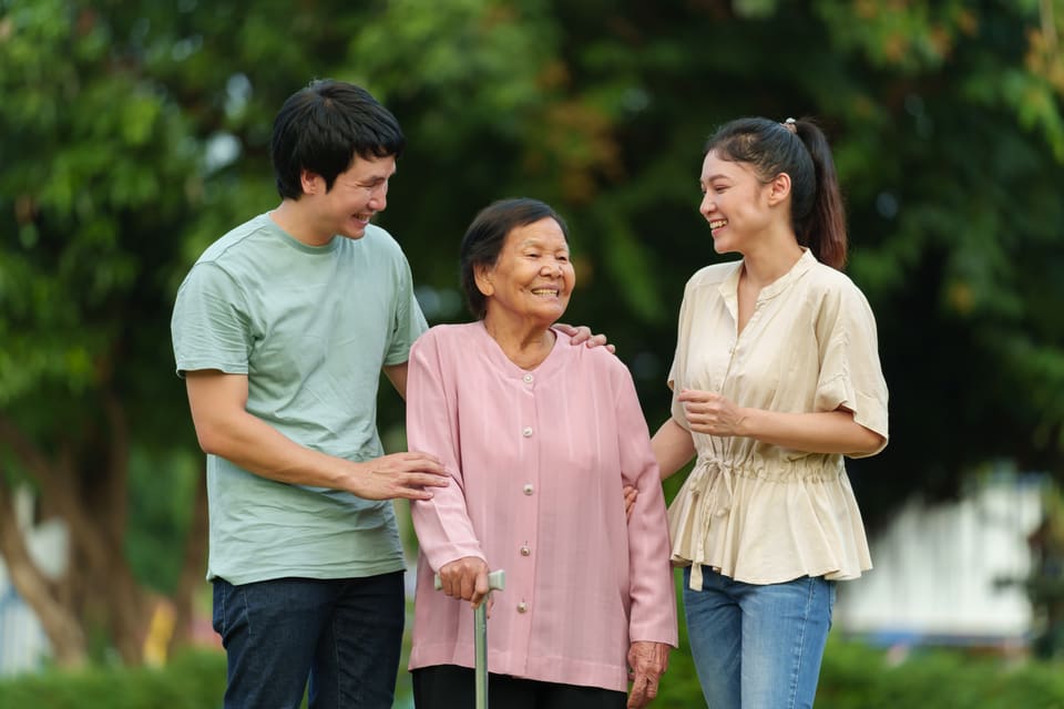 A family walking with an older woman in a garden