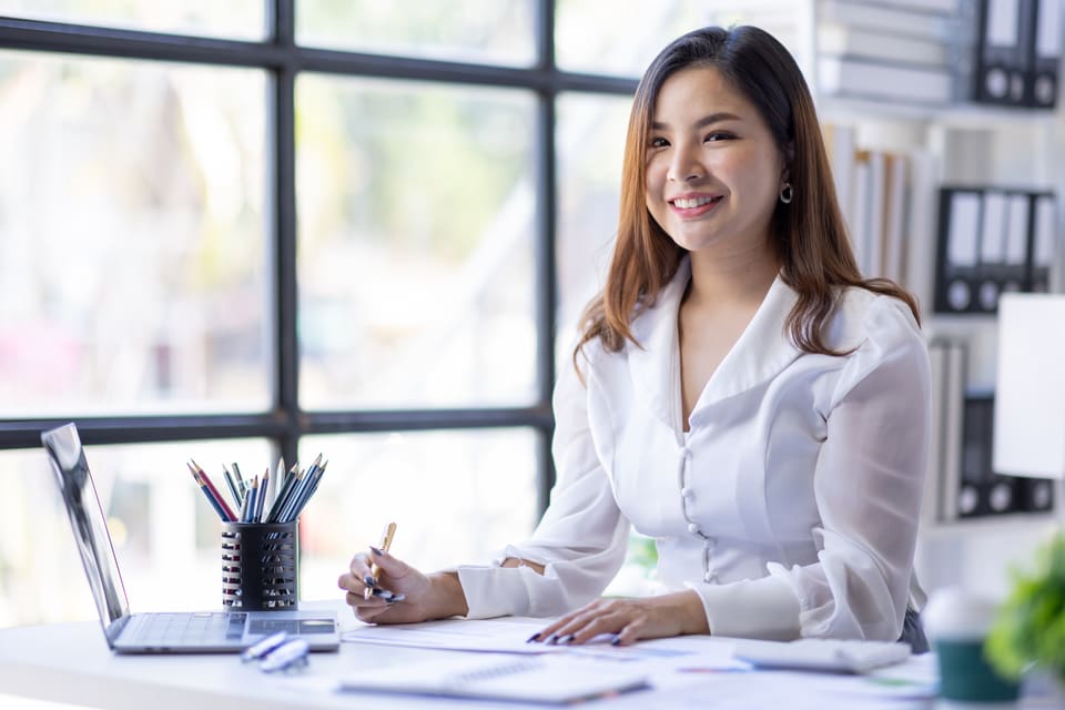 A smiling woman at her desk with paperwork