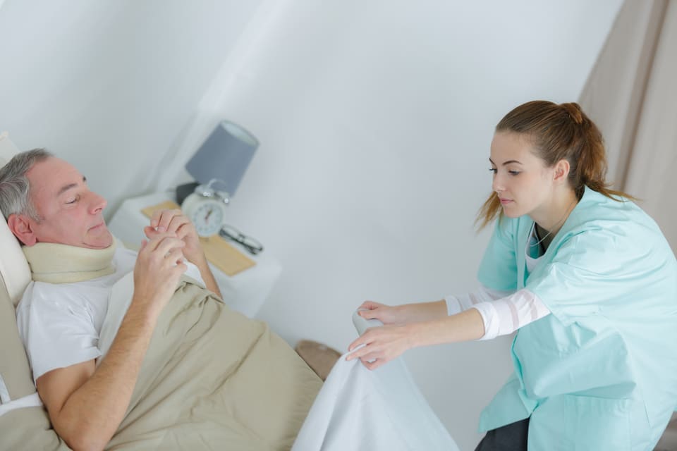 A carer helping a man settle in bed
