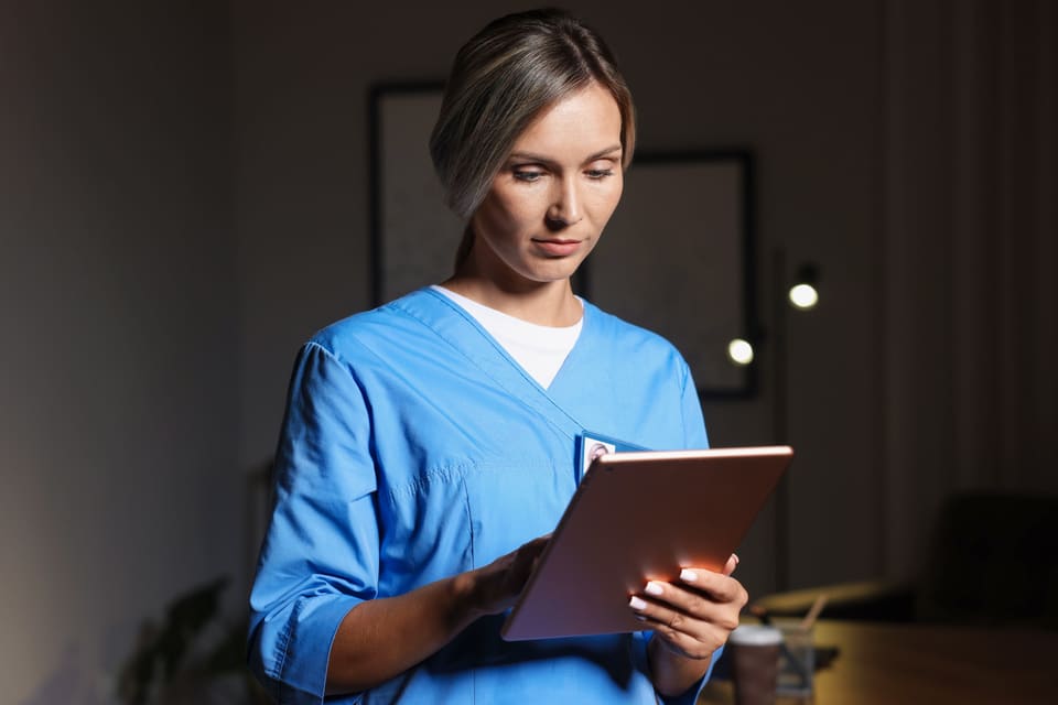 A carer reading a tablet in the evening