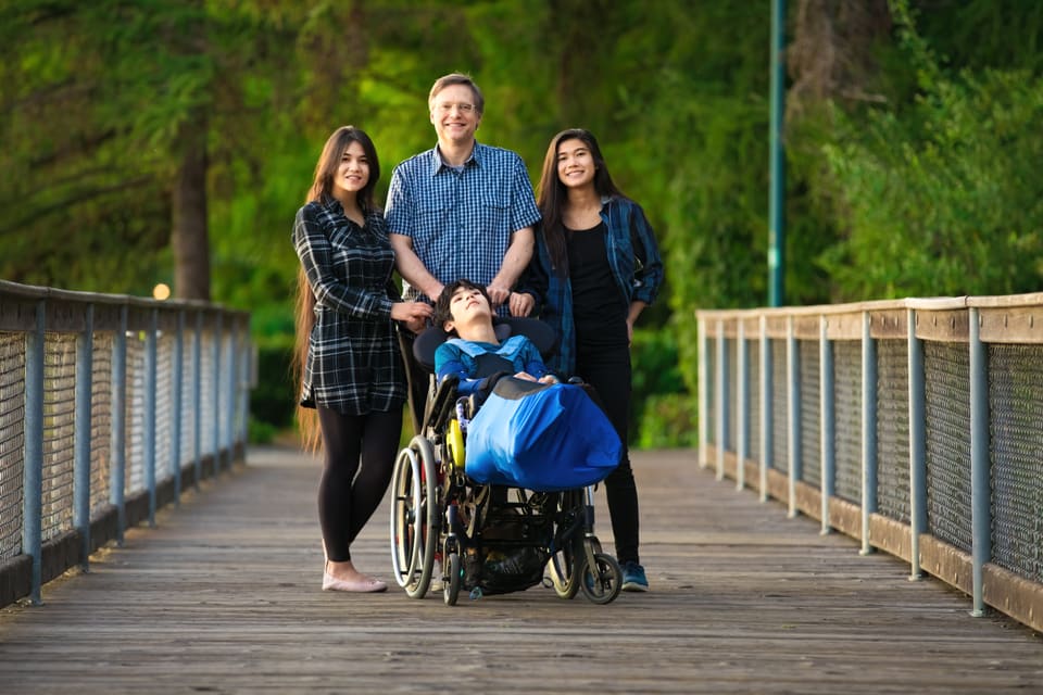 A family out walking on a boardwalk with a teenager in a wheelchair