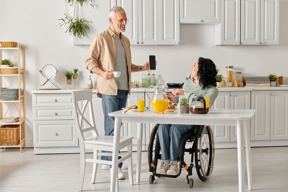 A woman in a wheelchair and a man sharing breakfast in a bright kitchen