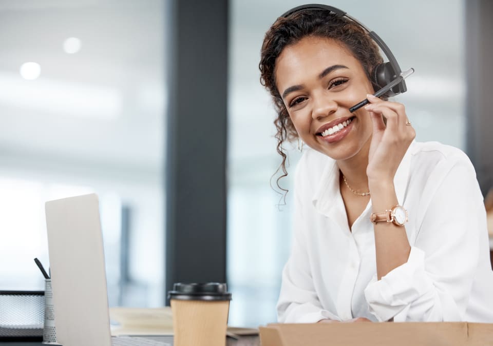 A smiling coordinator on a headset at her laptop