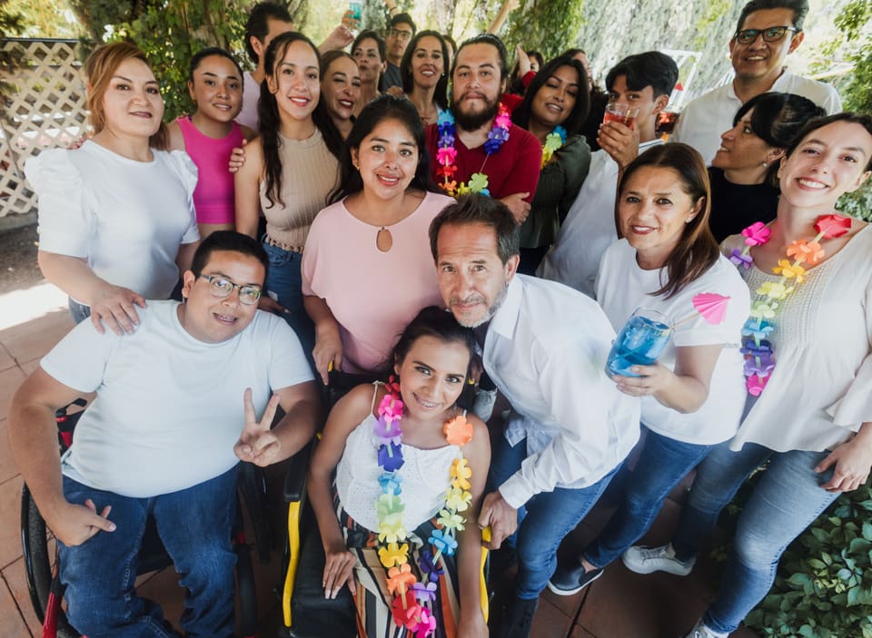 A big smiling group of friends and support staff celebrating together