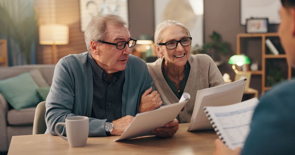 An older couple at home going through their paperwork with a visitor